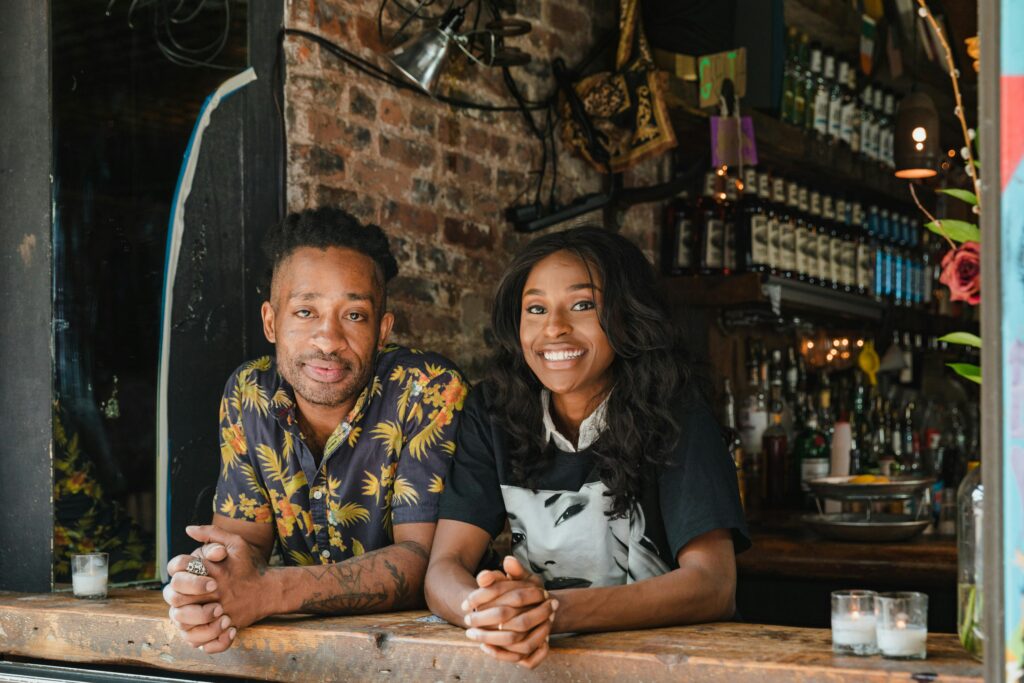 Two smiling small business owners at their shop, representing thousands who trust Lumen Point Capital